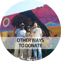 Other Ways to Donate - Photo: Three people smiling outside of a building with a large mural.